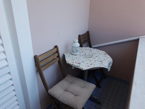 a small table with two chairs and a table with a bottle on it at Apartmani Zorica in Rab