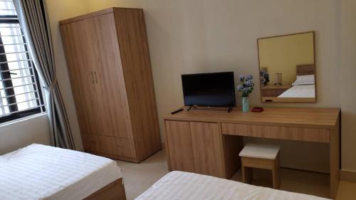 Schlafzimmer mit einem Schreibtisch, einem TV und einem Spiegel in der Unterkunft Latte Motel in Dong Hoi