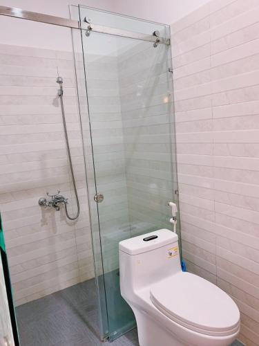 a bathroom with a toilet and a glass shower at Gallery Homestay in Quy Nhon