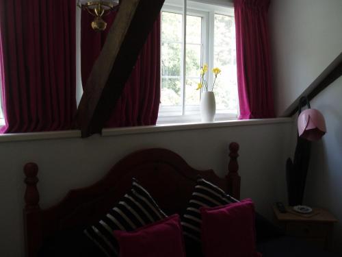 a bedroom with a bed and a window with red curtains at The Old Forge Seafood Restaurant and Bed and Breakfast in Thursford