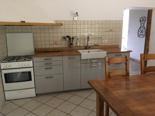 Il comprend une cuisine équipée d'une cuisinière, d'un évier et d'une table. dans l'établissement Maison Bourtoulot, à Mérilheu