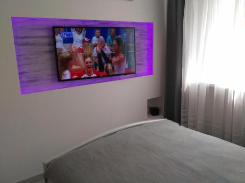 TV colgada en una pared sobre una cama en Apartament UnoPuro w centrum Giżycka, en Giżycko