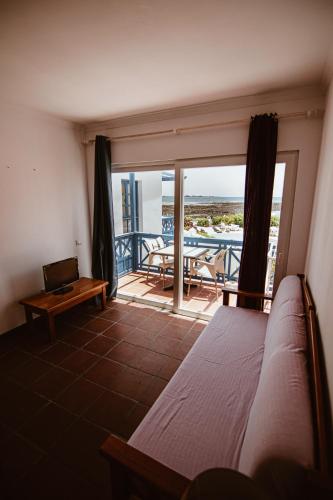 a bedroom with a bed and a balcony with a table at Apartamentos Punta Elena Beach in Corralejo