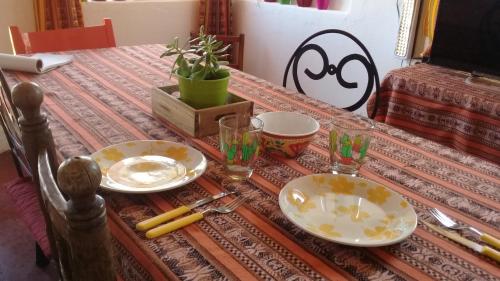una mesa con platos y vasos encima en Cabaña El Cardón,casita en el campo quebradeño en Humahuaca