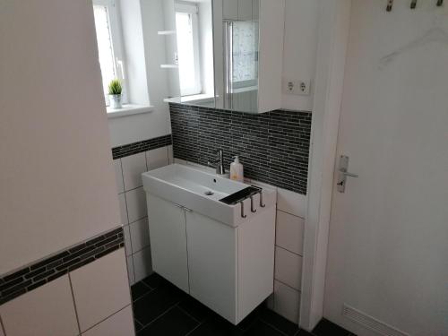 a white bathroom with a sink and a mirror at Apartment Kieselsgrund in Dielheim