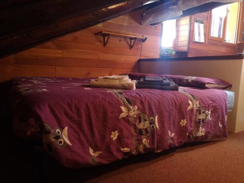 Cama en habitación con manta morada en Casetta Chamois, en Chamois