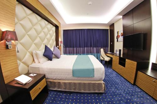 a hotel room with a large bed and a television at Armada Avenue Hotel - formerly Armada BlueBay Hotel in Dubai