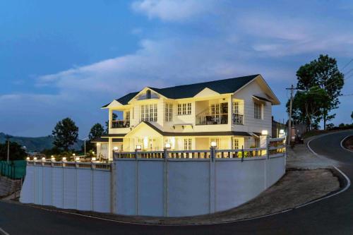 a house behind a fence on a road at StayVista at Aashirwaad Villa in Coonoor