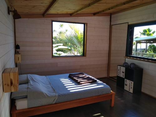 1 dormitorio con 1 cama en una habitación con 2 ventanas en Bungalow cosy avec piscine surplombant l'océan, en Bellemène