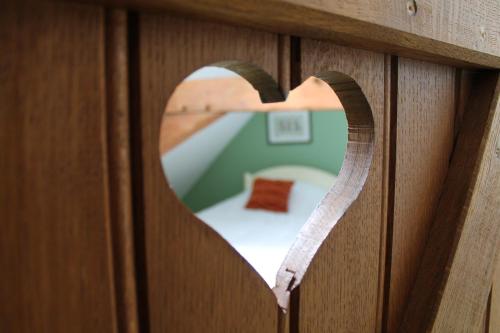 a heart shaped hole in a wooden wall with a bedroom at Châtellerie De Schoebeque in Cassel