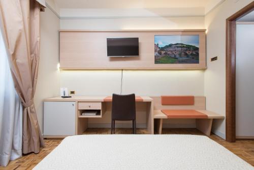 a bedroom with a desk and a tv on a wall at Hotel San Francesco in Rende