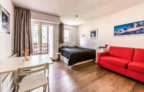 - un salon avec un canapé rouge et un lit dans l'établissement maeva Home Résidence la Rivière, à Chamonix-Mont-Blanc