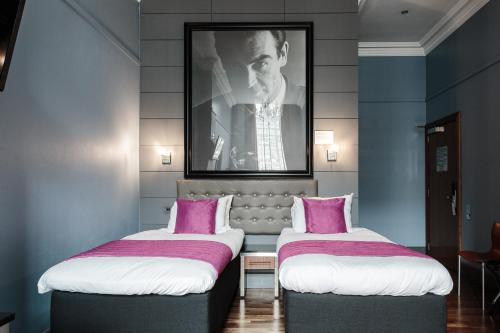 2 Betten in einem Zimmer mit einem Bild an der Wand in der Unterkunft Angels Share Hotel in Edinburgh