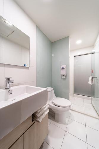 a white bathroom with a sink and a toilet at Fish Hotel - Yancheng in Kaohsiung