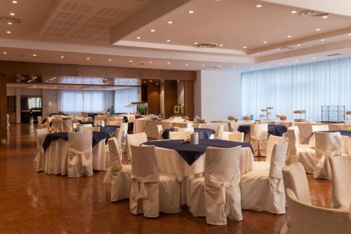 a banquet hall with white tables and white chairs at Hotel San Francesco in Rende