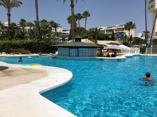 a pool at a resort with people in the water at Apartamentos Costa Lago Playamar in Torremolinos