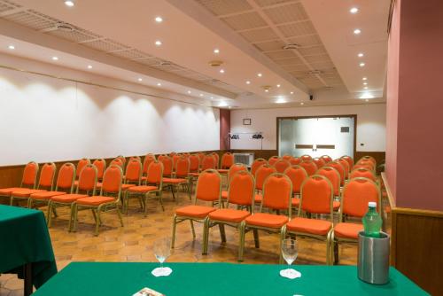 a conference room with orange chairs and a white screen at Hotel San Francesco in Rende