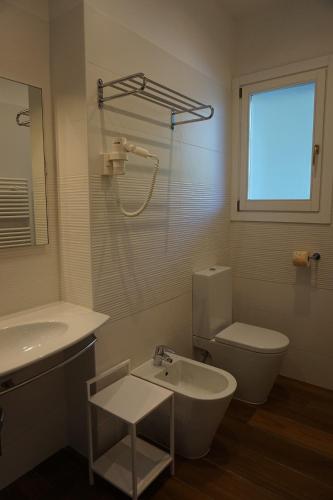 a bathroom with a sink and a toilet and a window at Villaggio Mare Blu in Bibione