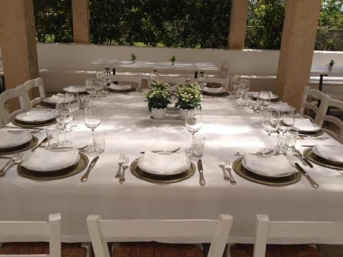 a long white table with glasses and plates and silverware at Masseria Montelauro in Otranto