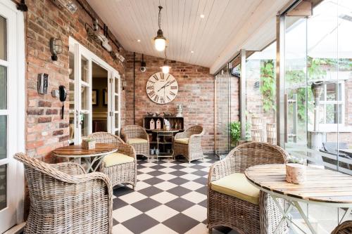 a restaurant with wicker chairs and tables and a clock at Eleven Didsbury Park Hotel in Manchester