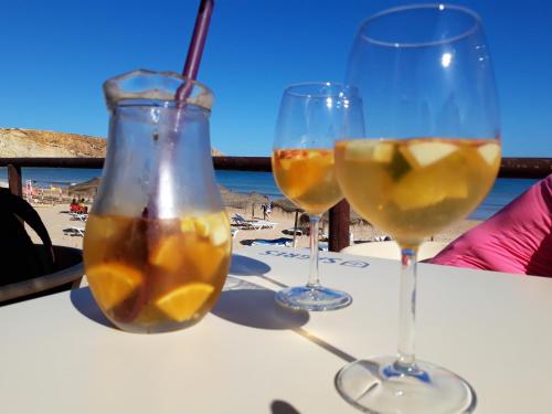 three glasses of wine sitting on a table with the beach at Sea Sagres in Sagres