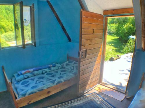 a bedroom with a bed in a blue room with a door at Kamp Vrbnica in Pluzine