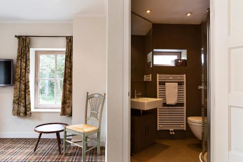 een badkamer met een wastafel, een toilet en een stoel bij Bosvilla Kennemerduinen in IJmuiden