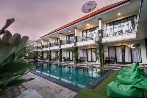 a hotel with a swimming pool in front of a building at Kamandhani Cottage in Ubud