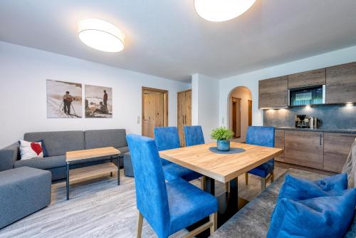 a living room with a table and blue chairs at B&B Appartement Das Stoaberg in Leogang