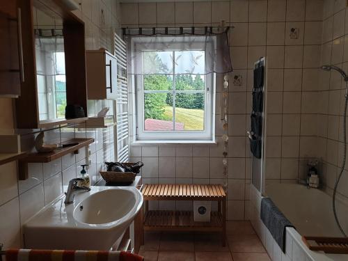 菲希特貝格的住宿－Ferienwohnung Fichtelmountain，一间带水槽和浴缸的浴室以及窗户。