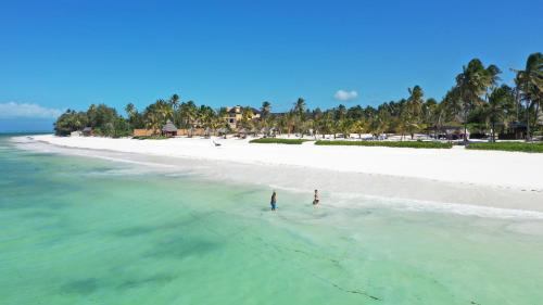 two people standing in the water on a beach at The Sands Beach Resort in Bwejuu