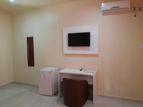 a room with a desk and a tv on the wall at HsHotelaria - Filial Bombinhas in Bombinhas