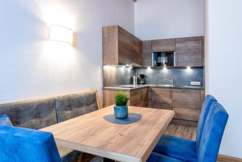 a dining room with a wooden table and blue chairs at B&B Appartement Das Stoaberg in Leogang
