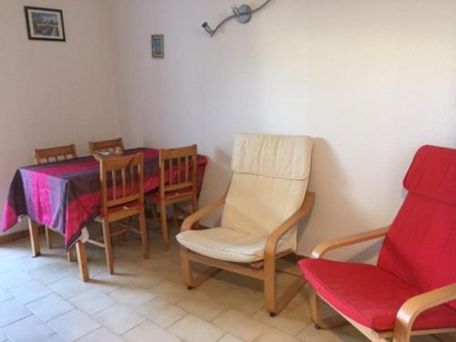 comedor con mesa y sillas, mesa roja y sillón en Studio Les Lecques 100m de la plage en Saint-Cyr-sur-Mer
