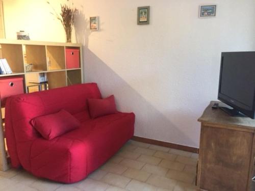 un sofá rojo en la sala de estar con TV en Studio Les Lecques 100m de la plage en Saint-Cyr-sur-Mer