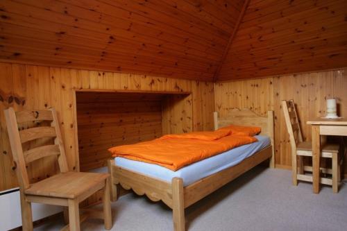 Cama en habitación de madera con mesa y sillas en Angel's sport - Le Central en Grône