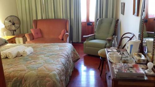 a bedroom with a bed and a chair and a table at Bougain Villa Guesthouse in Prince Albert