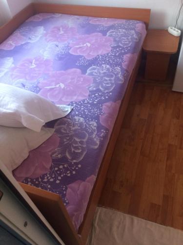 a bed with a purple and pink flower pattern on it at Pensiunea Everest in Craiova