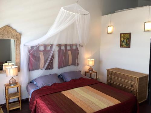 Schlafzimmer mit einem Bett mit einer roten Tagesdecke in der Unterkunft BAY VIEW MARTINIQUE in Les Anses-dʼArlets