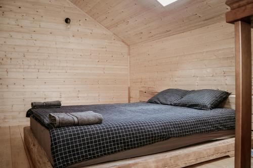 a bedroom with a bed in a wooden wall at Atpūtas Bāze Ods LOFTS in Bārta
