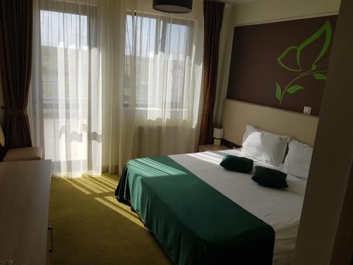 a hotel room with a bed with green sheets and pillows at Papillon in Piteşti
