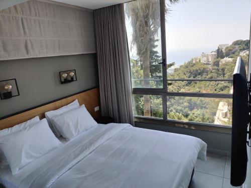 a bedroom with a bed and a large window at Luxury Suites by Notaly Ariel in Haifa