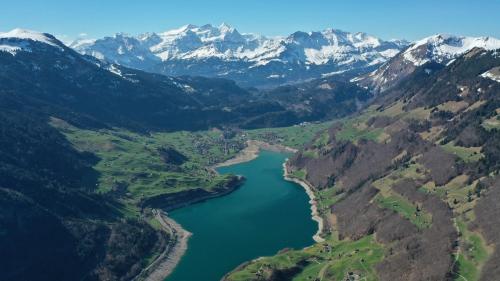 an aerial view of a river in a valley with snowy mountains at Emma's B&B - Self Check-in Hotel in Lungern