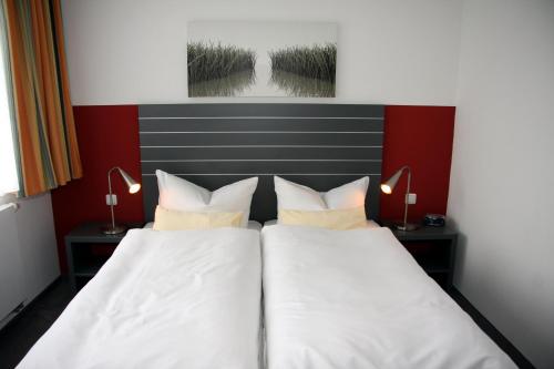 two beds in a hotel room with white sheets and pillows at Landhotel Wieseneck in Winterfeld