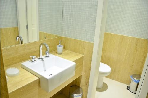 a bathroom with a sink and a toilet and a mirror at Capri Hotel in Duque de Caxias