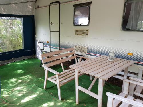 a wooden table and bench in a room with green grass at Przyczepy Kemping Polaris Półwysep Helski in Chałupy