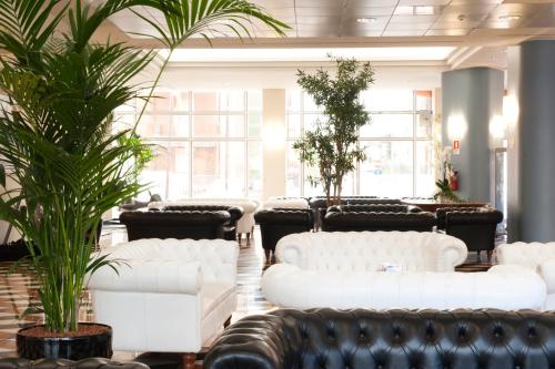una fila di divani bianchi in una stanza con piante di Montresor Hotel Tower a Bussolengo