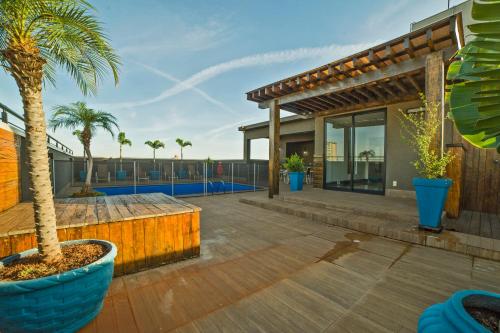 a deck with a palm tree and a house at Hotel Leiria in Matão