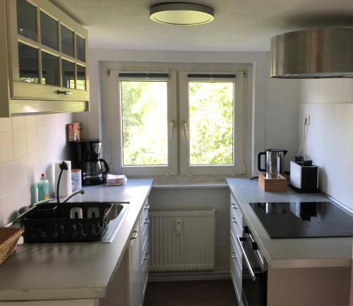 a kitchen with white counters and a sink and two windows at Budapester Hof Gästehaus in Hamburg