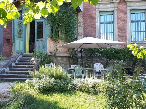 a table and chairs with an umbrella in front of a house at Rózsilak in Balatonfüred